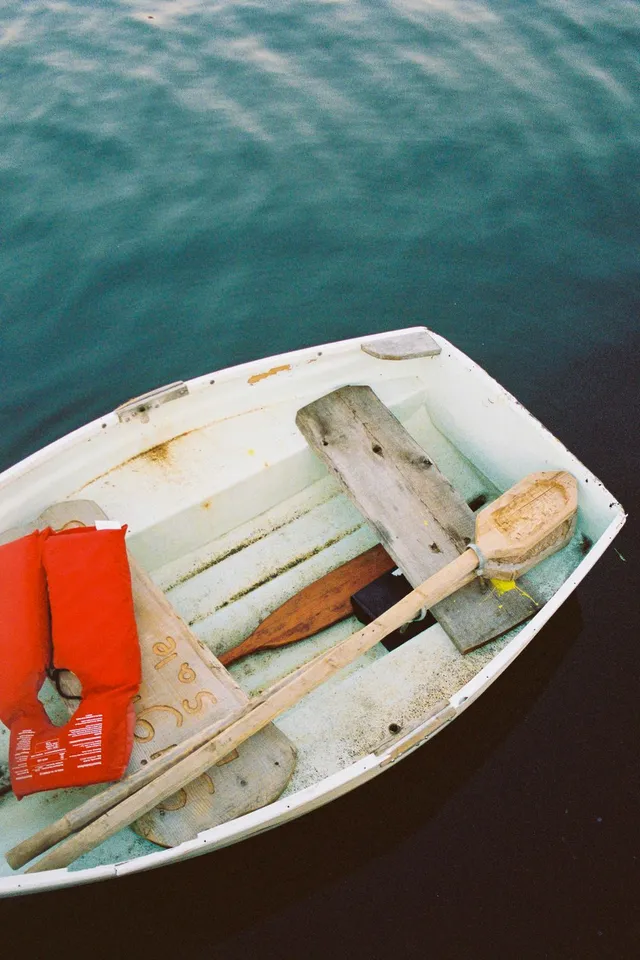 Looking down into a small white rowboat with oars and a red life jacket