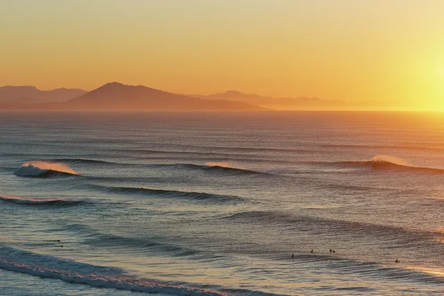 Lines of surf at sunset under hazy mountains