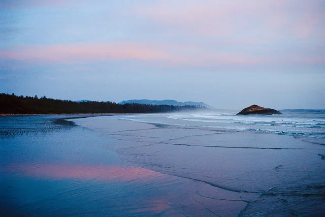 Misty beach at dusk, pink light on wet sand and a small island offshore