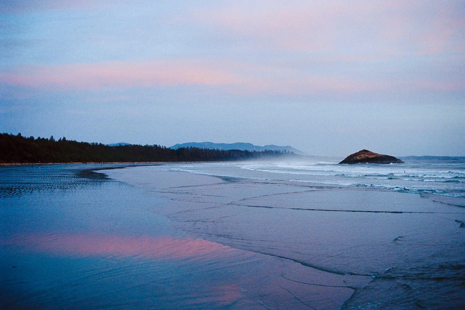 Misty beach at dusk, pink light on wet sand and a small island offshore