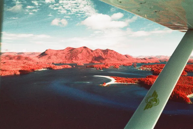 Red-tinted mountains and an inlet seen past a plane's wing strut
