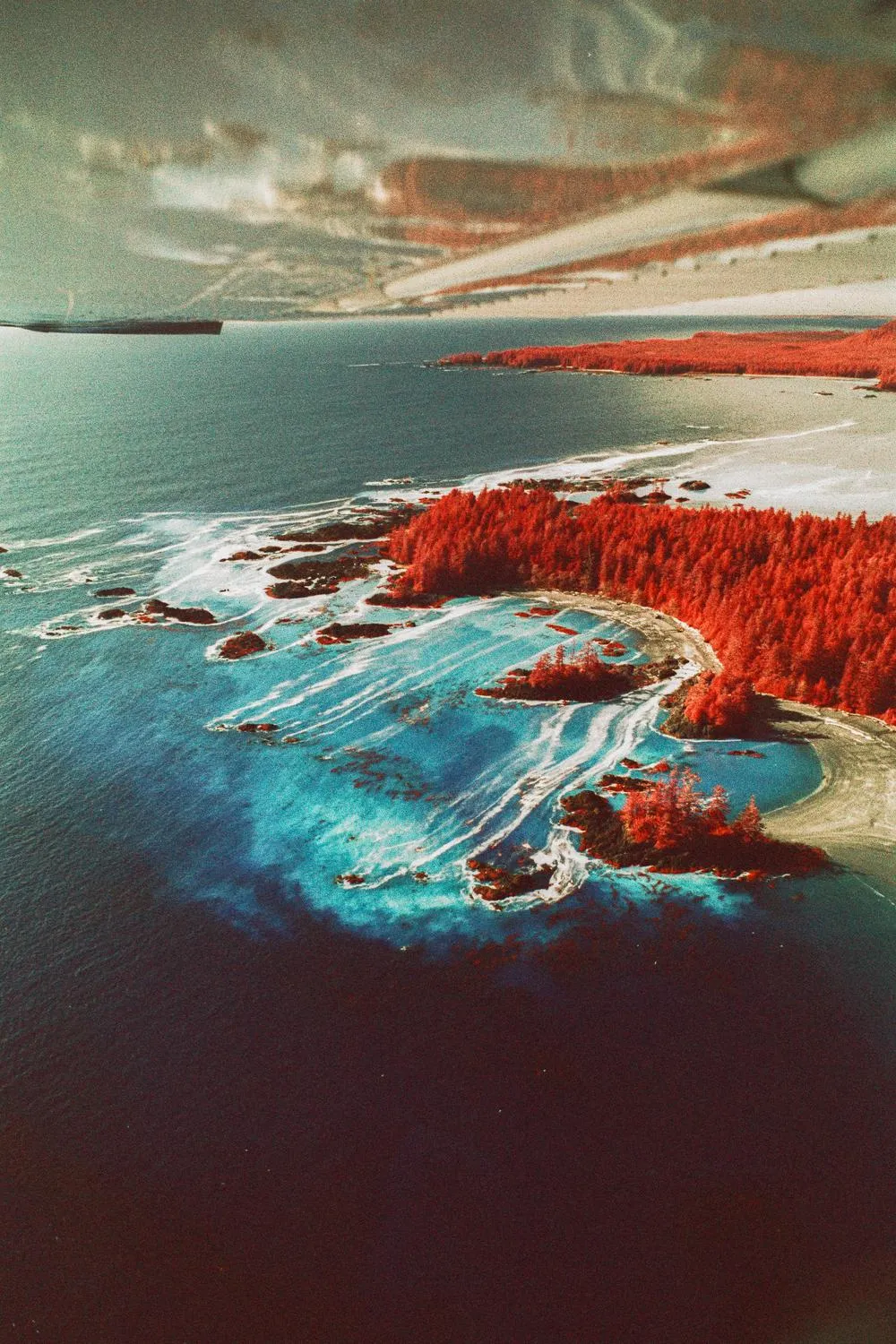 Aerial view of red-forested islands and turquoise surf