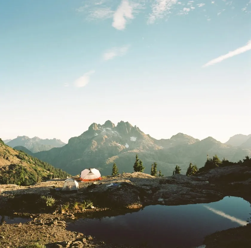 Tents on a rocky ridge below a jagged peak
